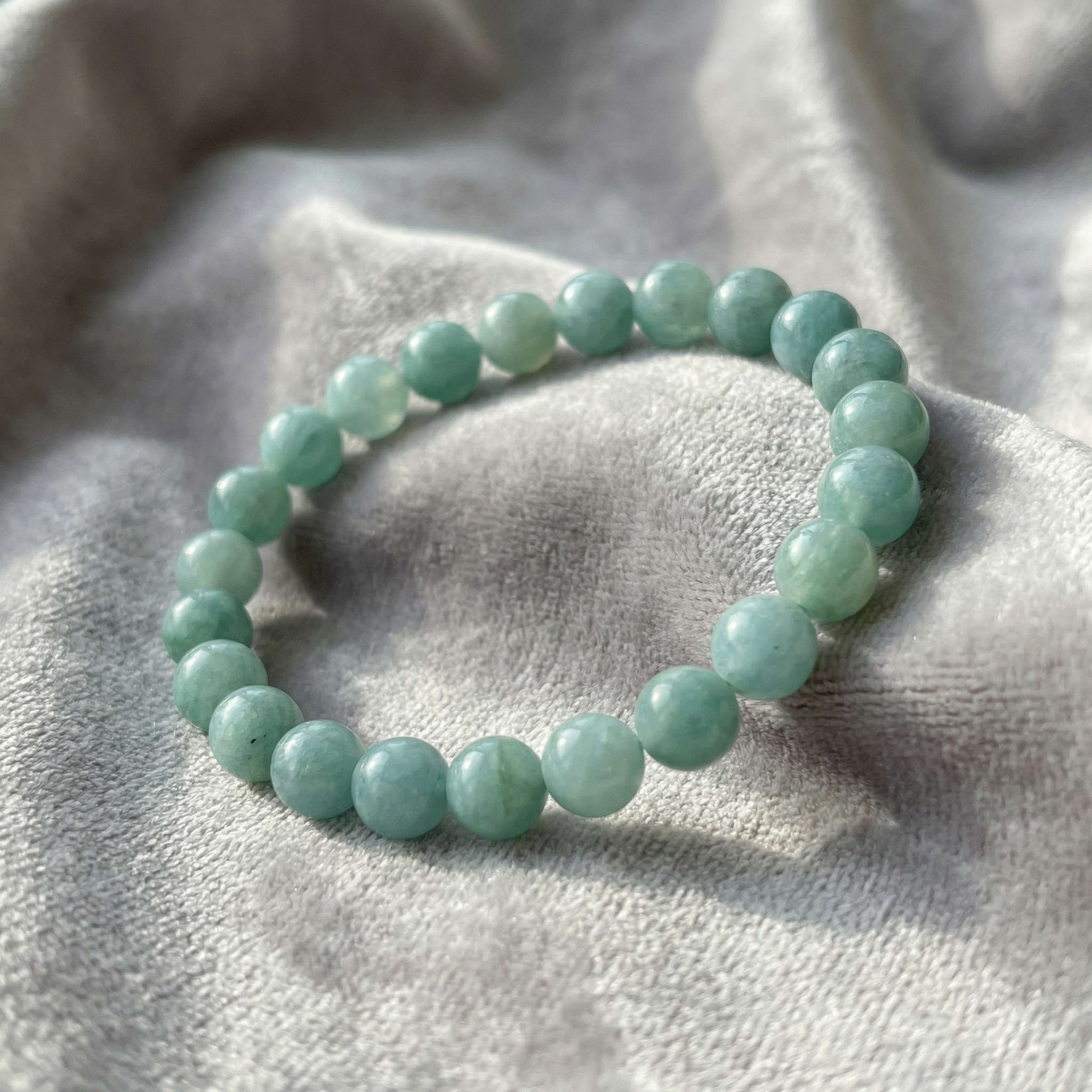 Aqua beaded bracelet on a textured gray fabric background
