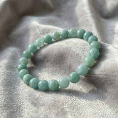 Aqua beaded bracelet on a textured gray fabric background